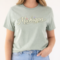 Person wearing a light green t-shirt with 'Michigan' printed on it, standing against a plain background.